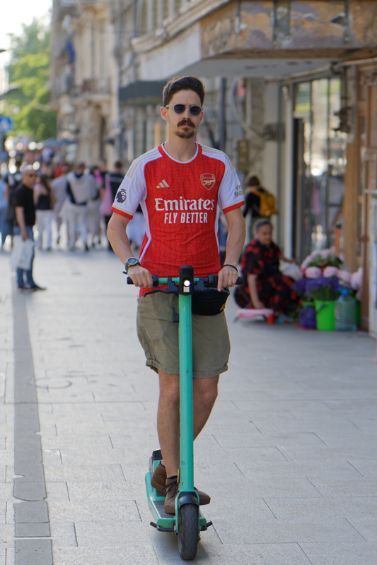 2 - Young man navigating a bustling city street on a shared electric scooter